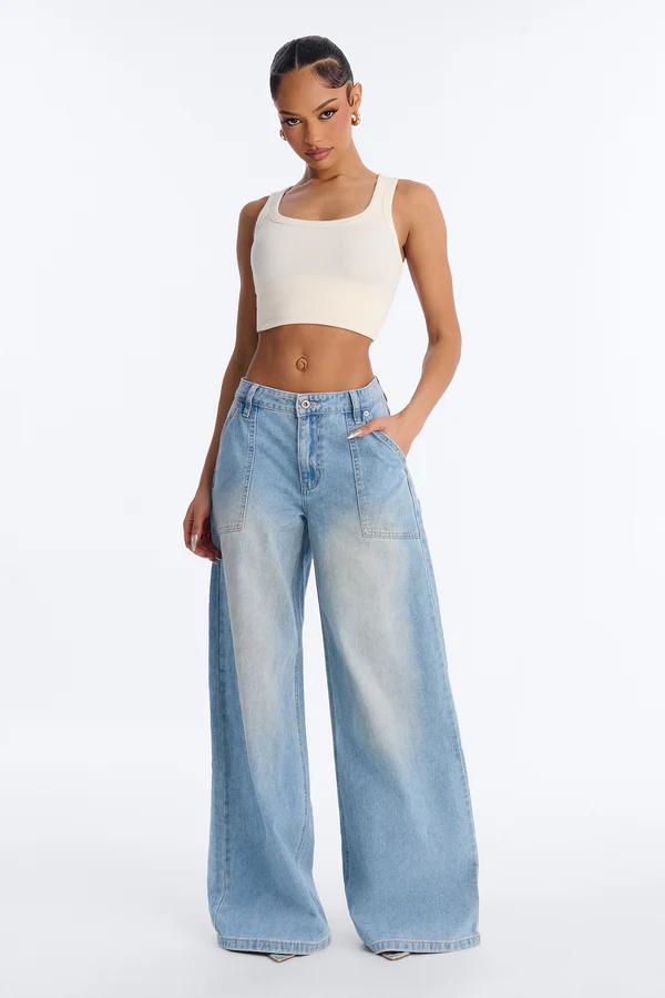 Woman modeling a cream square-neck crop top and faded light blue wide-leg jeans with utility pockets on a white background.