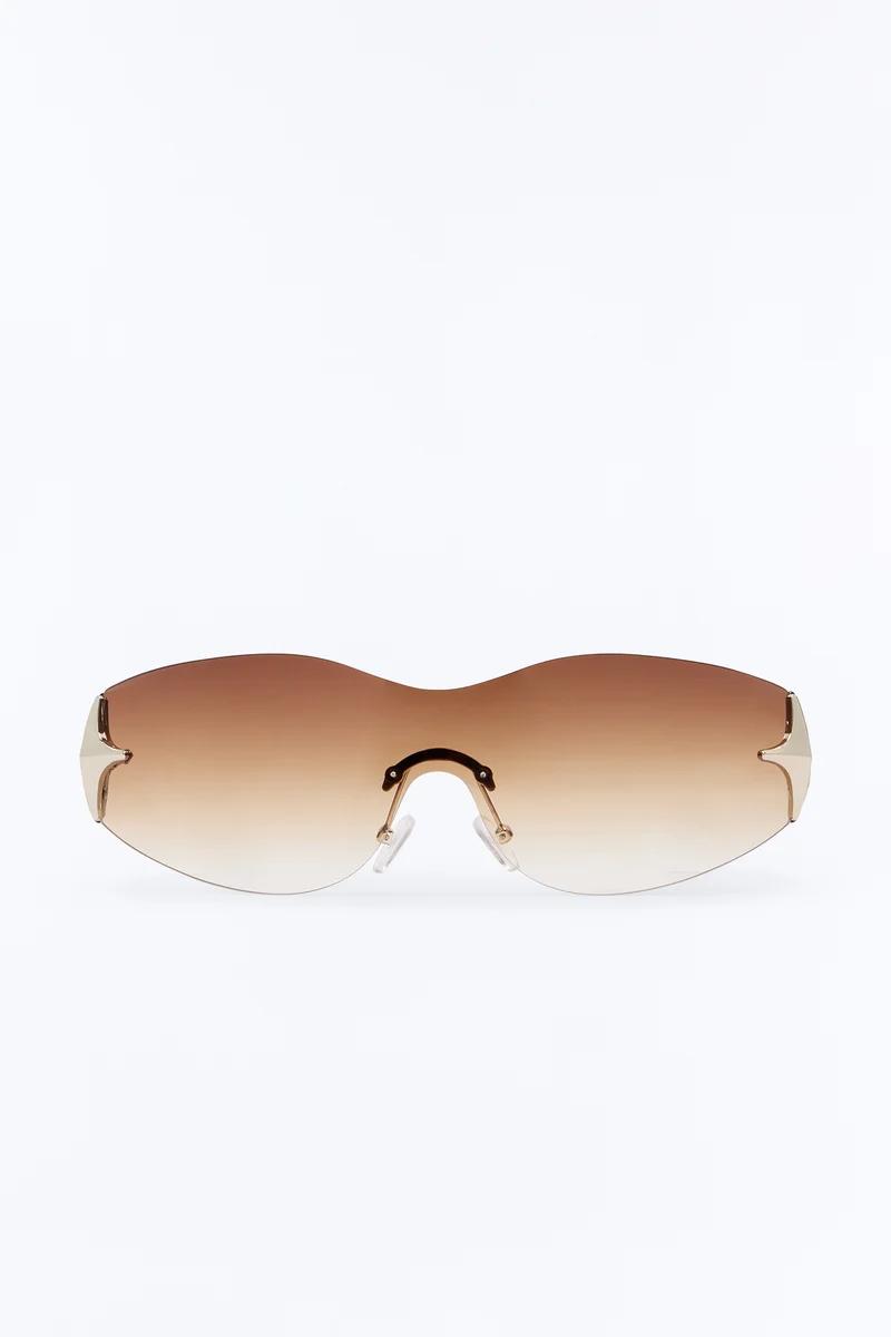Modern rimless sunglasses with brown gradient shield lenses and gold accents.