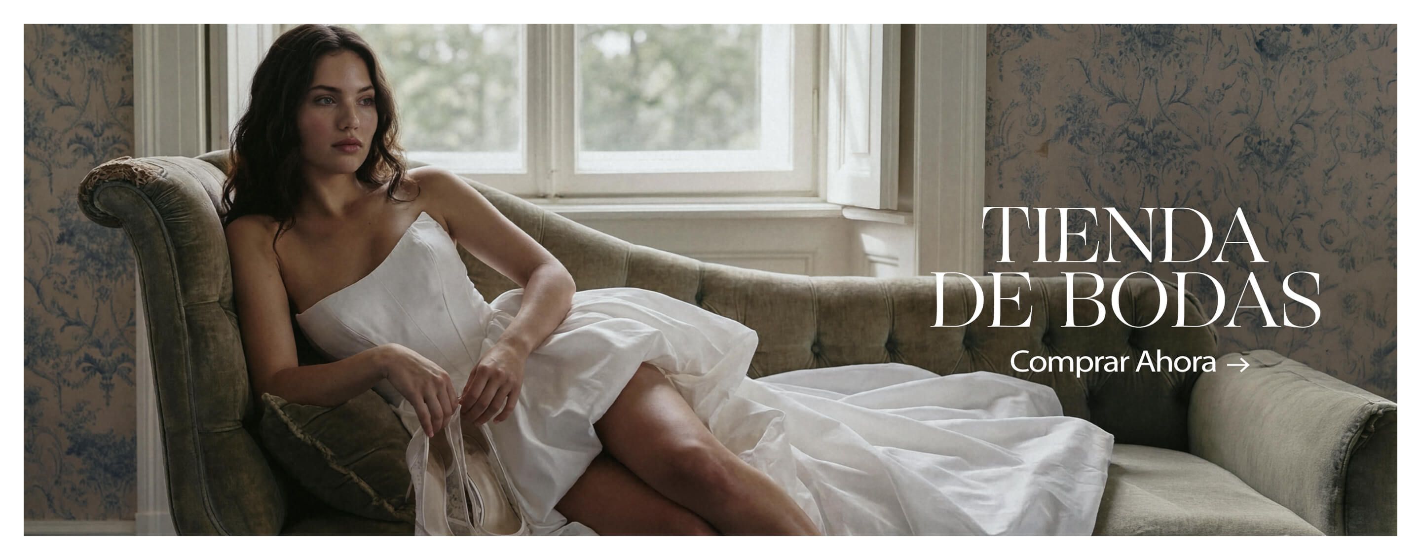 Mujer en top blanco sobre sofá verde oliva, sujetando elegantes tacones de novia con perlas. Promueve la colección Wedding Suite. Compra zapatos nupciales.