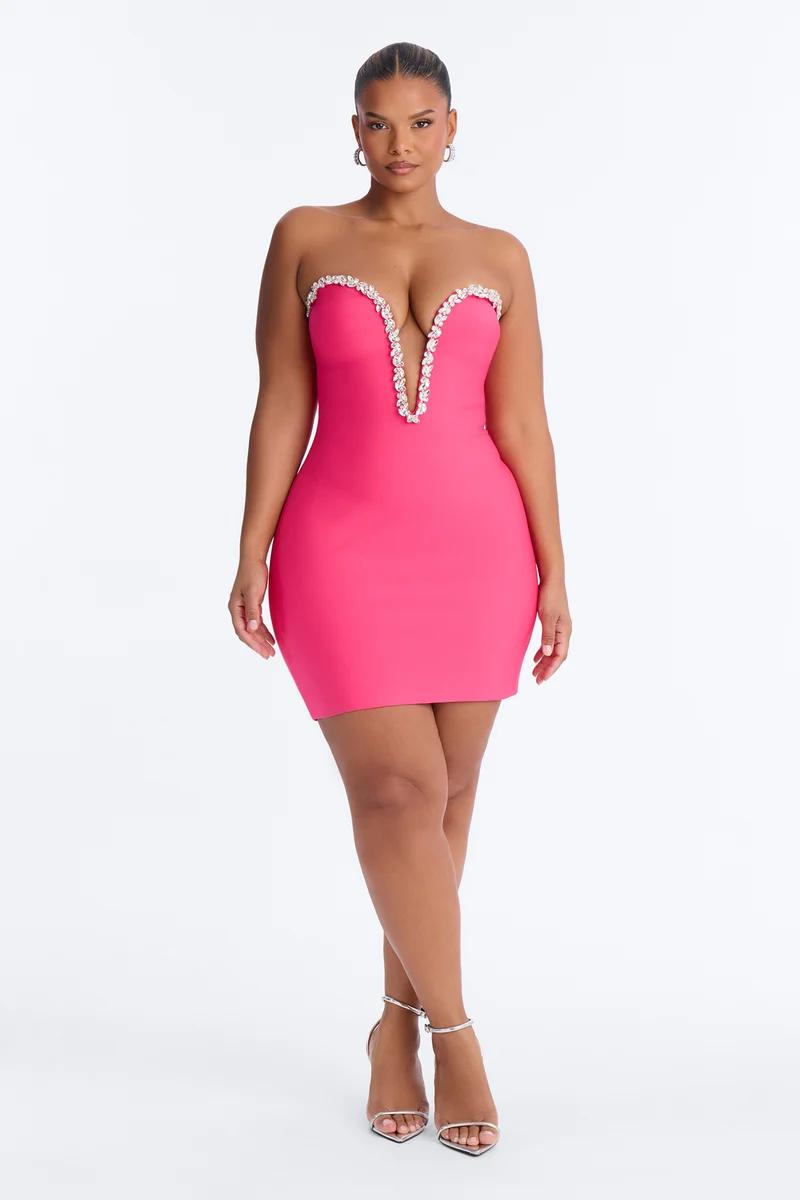 Curve model wearing a hot pink strapless mini dress with a crystal plunge neckline and silver heels for a chic cocktail party fashion look.