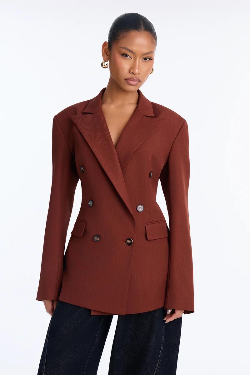 Woman wearing a tailored rust brown double-breasted blazer jacket.