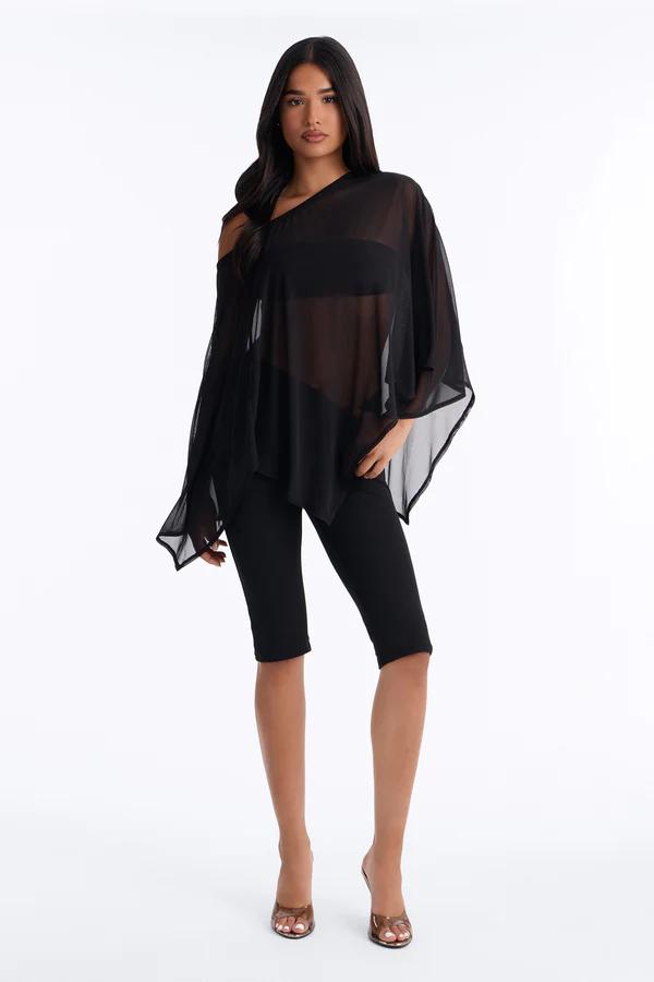 Woman showcases a trendy orange wrap plunge top and matching cropped pants set. Complemented by silver heels and an elegant bag for a chic look.