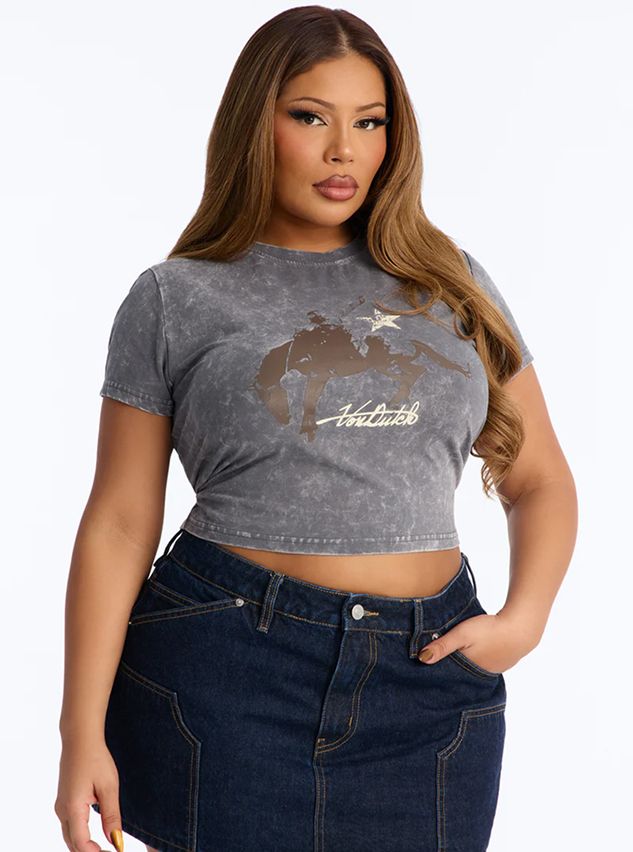 Plus-size model in a distressed gray Von Dutch crop top with a brown graphic and dark denim mini skirt, promoting trendy casual fashion.