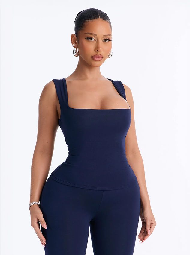 Model wears a sleek navy blue square-neck tank top and matching leggings from the new activewear collection against a white background.
