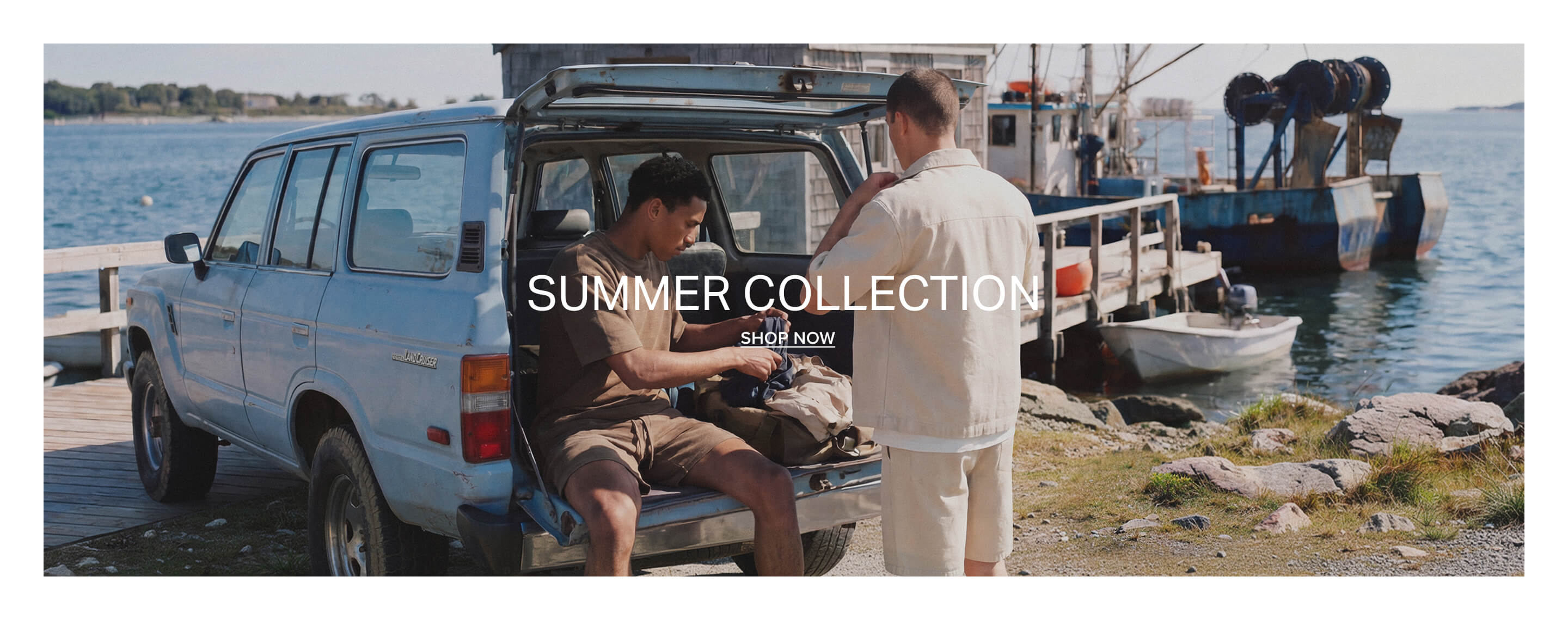 Two men with a vintage car, packing casual men's summer clothes: brown t-shirt & shorts, beige shirt & shorts. Discover our new summer collection.