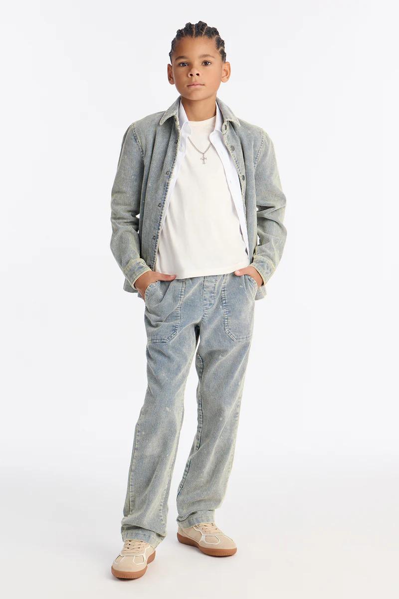 Young boy in light blue washed corduroy jacket, white tee, matching pants, & sneakers. Casual kids' fashion.