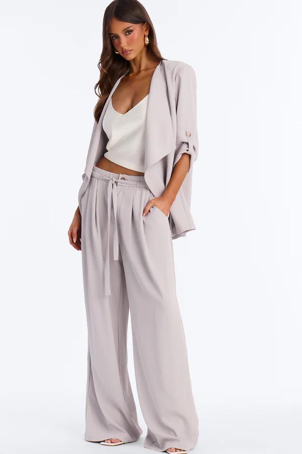 Stylish woman in a lavender co-ord set: open blazer, white crop top, and wide-leg pants. Perfect chic look for spring fashion.