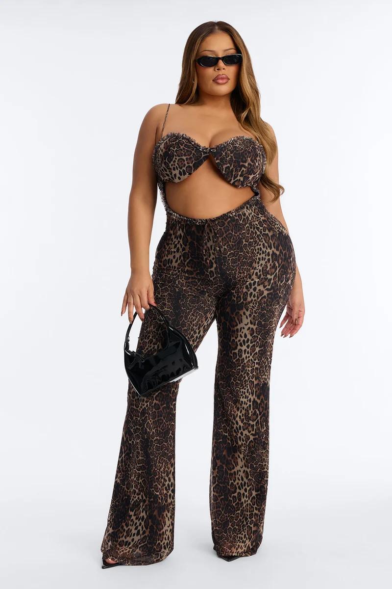 Woman modeling a pale yellow satin lace-trim romper and gold heels on a white background, promoting plus size sleepwear fashion.