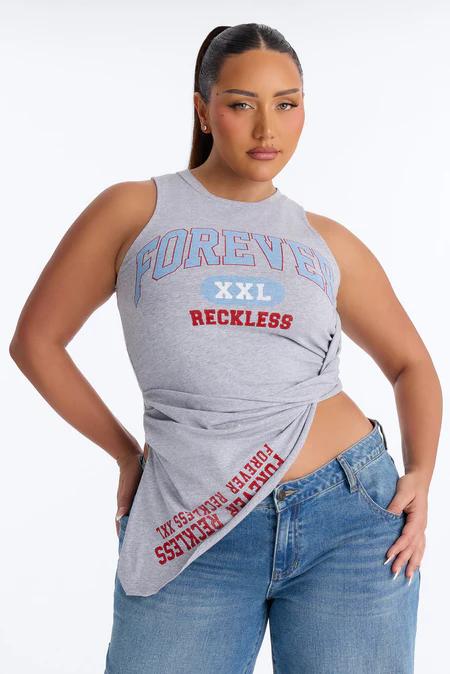 Mujer modelando un top sin mangas gris con gráfico "FOREVER XXL RECKLESS", metido en jeans azules, mostrando moda casual.