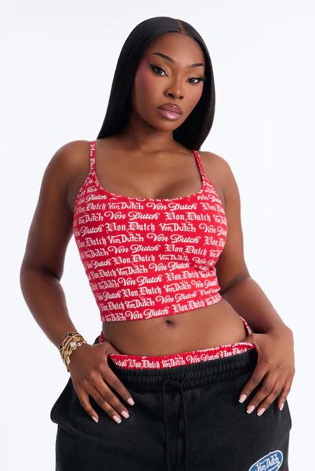 Mujer segura modela un vibrante top corto rojo con logo Von Dutch y pantalones deportivos negros, mostrando nuestra nueva colección de ropa urbana para mujer.