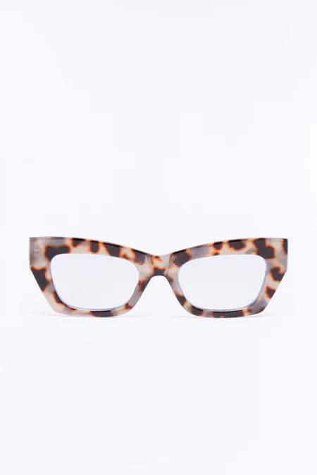 Dramatic cat-eye glasses with thick, angular brown and black leopard print frames, featuring clear lenses against a white background.