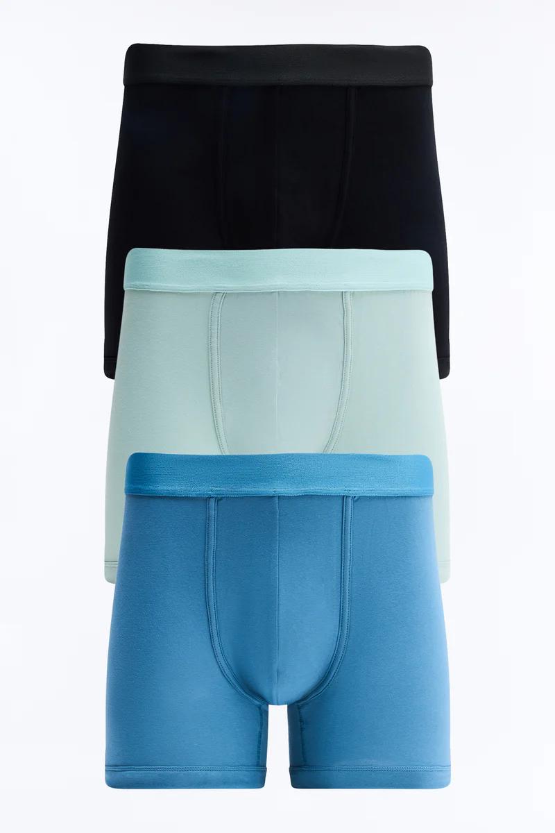 Stack of three essential men's boxer briefs: black, mint green, blue. Premium, comfortable everyday underwear collection.