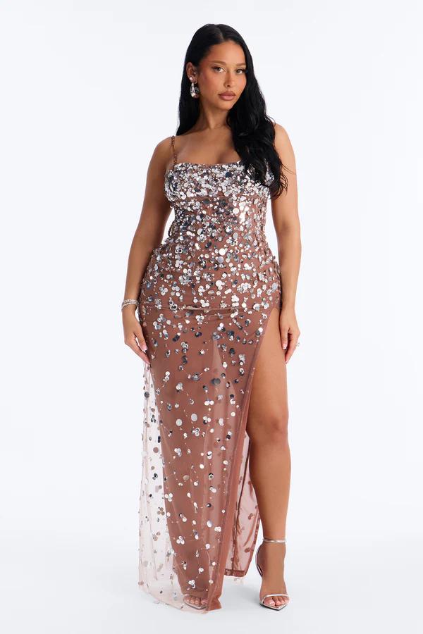 Woman wearing a brown sheer sequin maxi dress with a high leg slit, showcasing glamorous evening gowns from the new partywear collection.