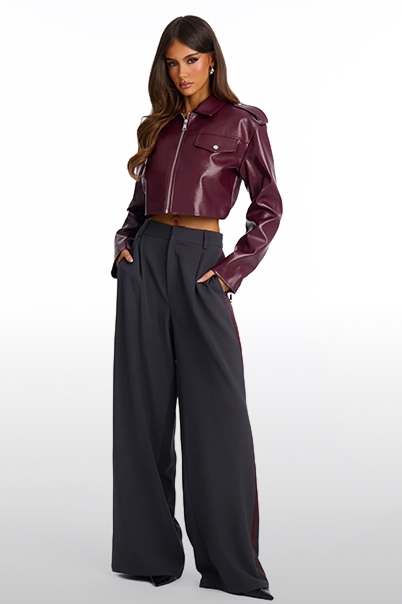 Model wearing a chic cropped burgundy faux leather jacket and dark grey wide-leg trousers showcasing trendy fall fashion apparel.