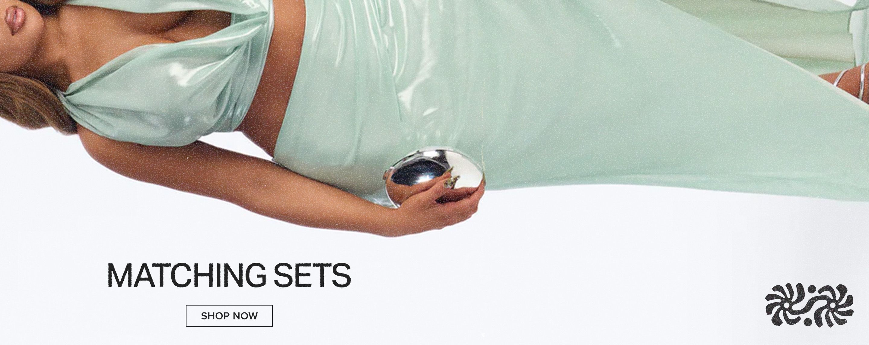 Woman models a shimmering mint green halter crop top and matching skirt holding a silver clutch. Promoting matching sets fashion. Shop now!