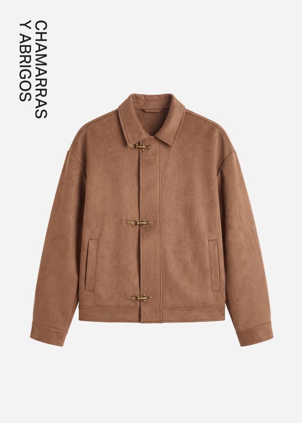 Chaqueta de antelina marrón con cierres de alamar metálicos dorados y cuello clásico, destacada como prenda de abrigo premium para otoño.