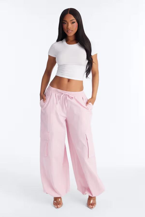 Mujer con top corto blanco y pantalones cargo anchos rosas. Conjunto casual de moda para mujer.
