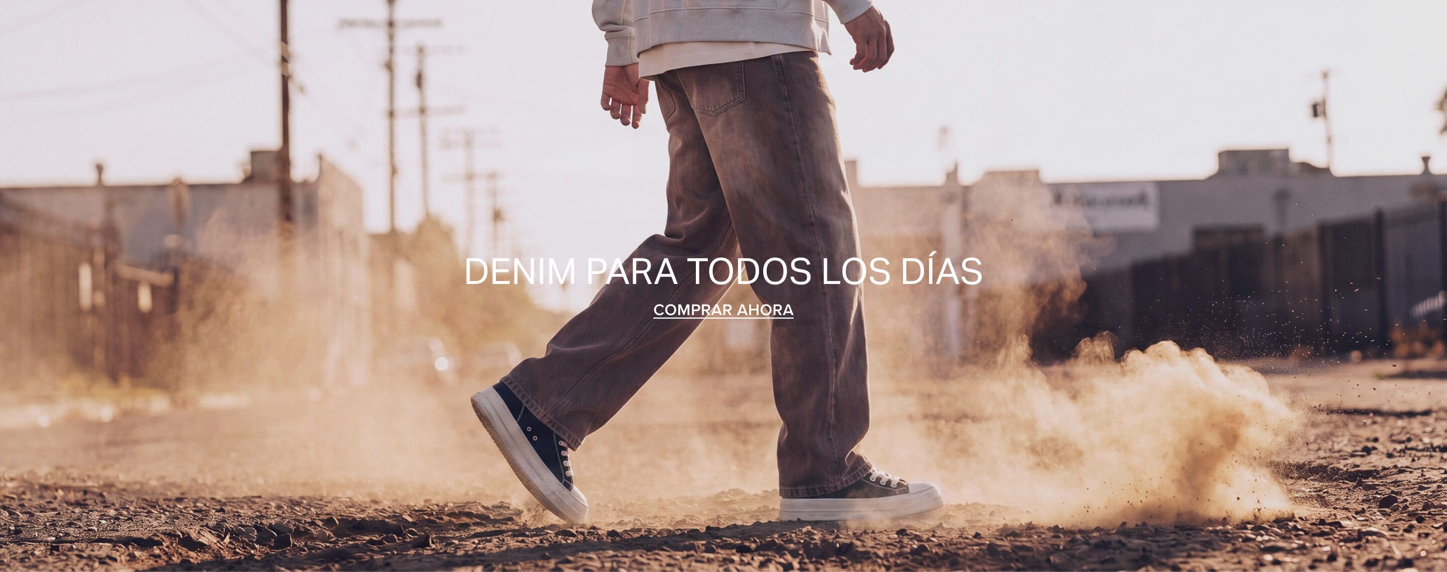 Persona caminando con vaqueros marrones de pierna ancha y zapatillas. Texto: 'Everyday Denim, Shop Now' que promueve moda urbana casual.