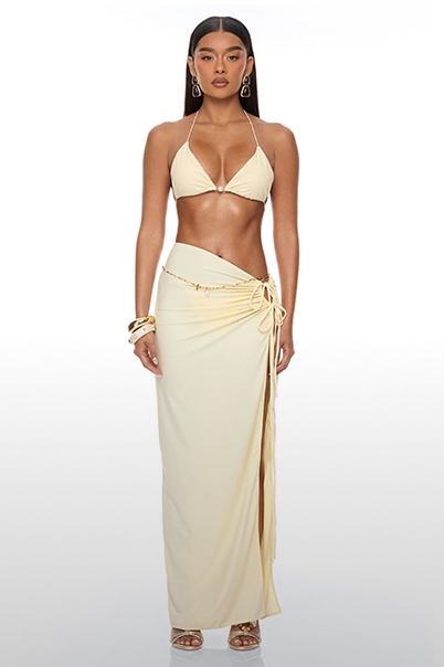 Modelo de cuerpo completo con top de bikini halter crema y falda maxi drapeada a juego, ideal para moda playera o resort de lujo.