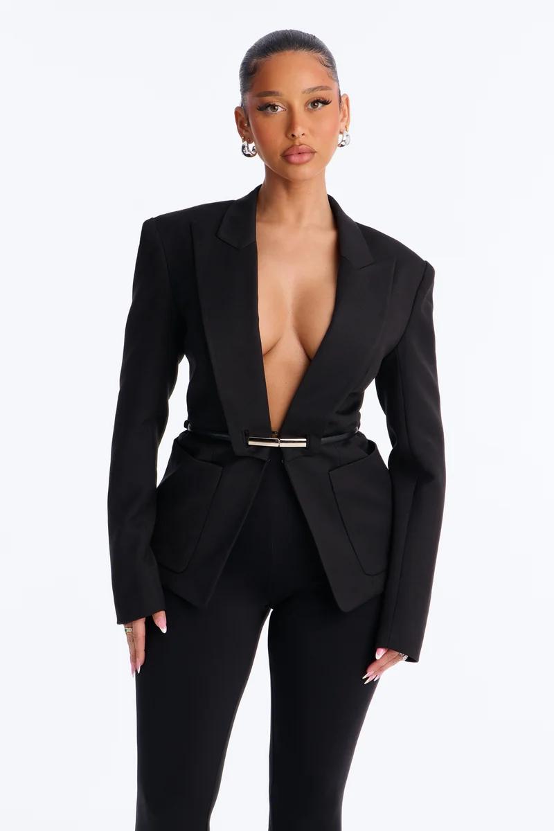 Elegant woman in a fitted black blazer with deep V-neck and gold belt, matching black trousers.