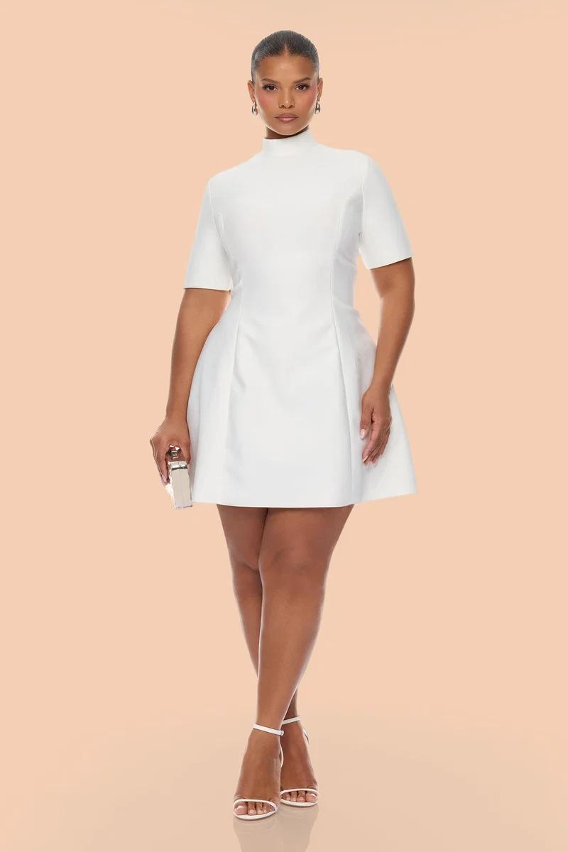 Elegant model in a high-neck white mini dress with heels and clutch, showcasing a chic bridal shower or cocktail party fashion look.