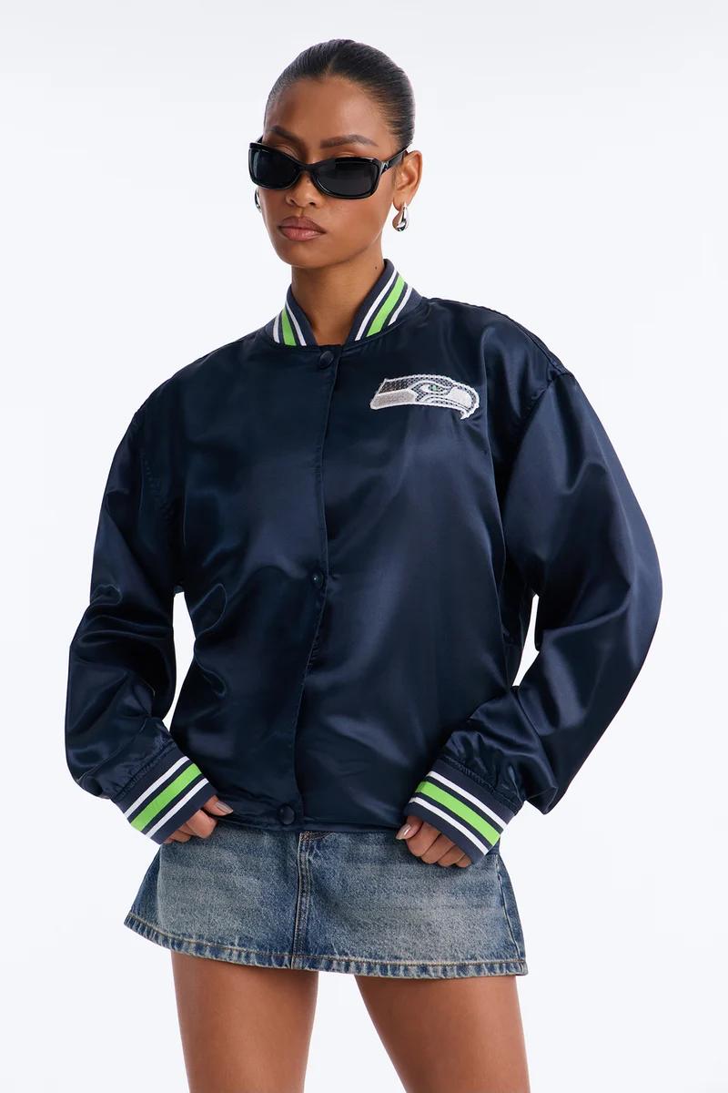 Woman wearing a navy blue satin Seattle Seahawks bomber jacket and denim miniskirt.