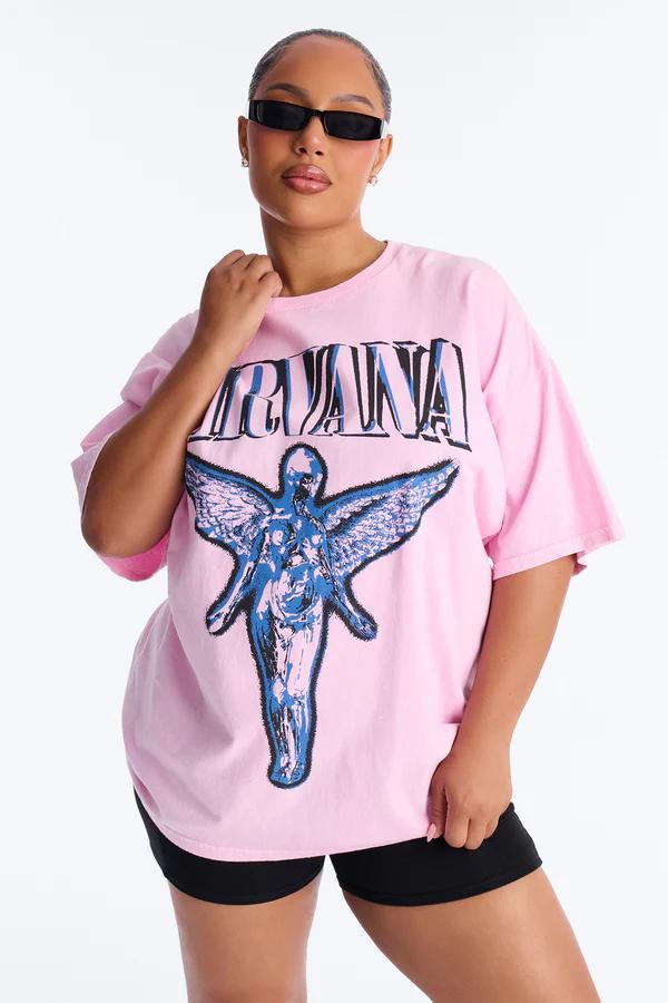 Woman in black sunglasses, wearing an oversized pink Nirvana t-shirt with a blue 'In Utero' angel graphic, standing in black shorts.