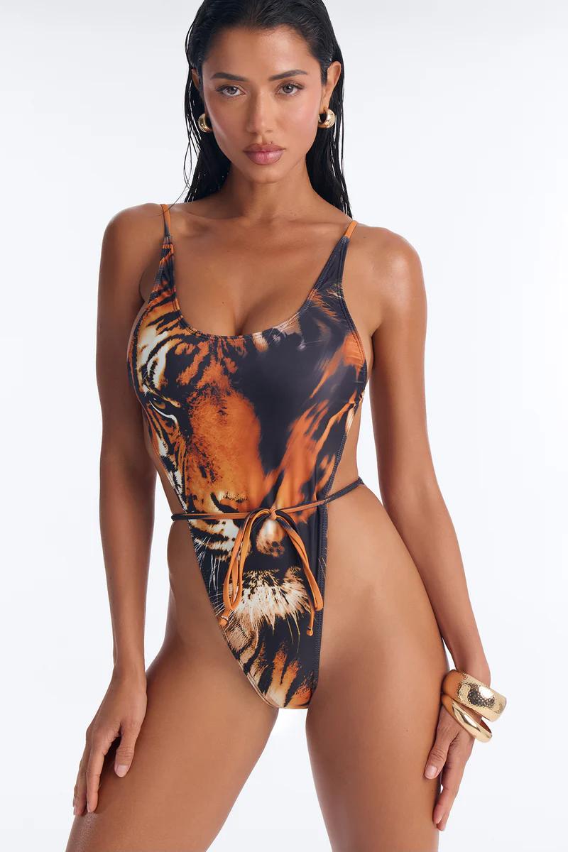 Glamorous model wears high-cut tiger face print monokini swimsuit with gold jewelry. Perfect for beach and resort.