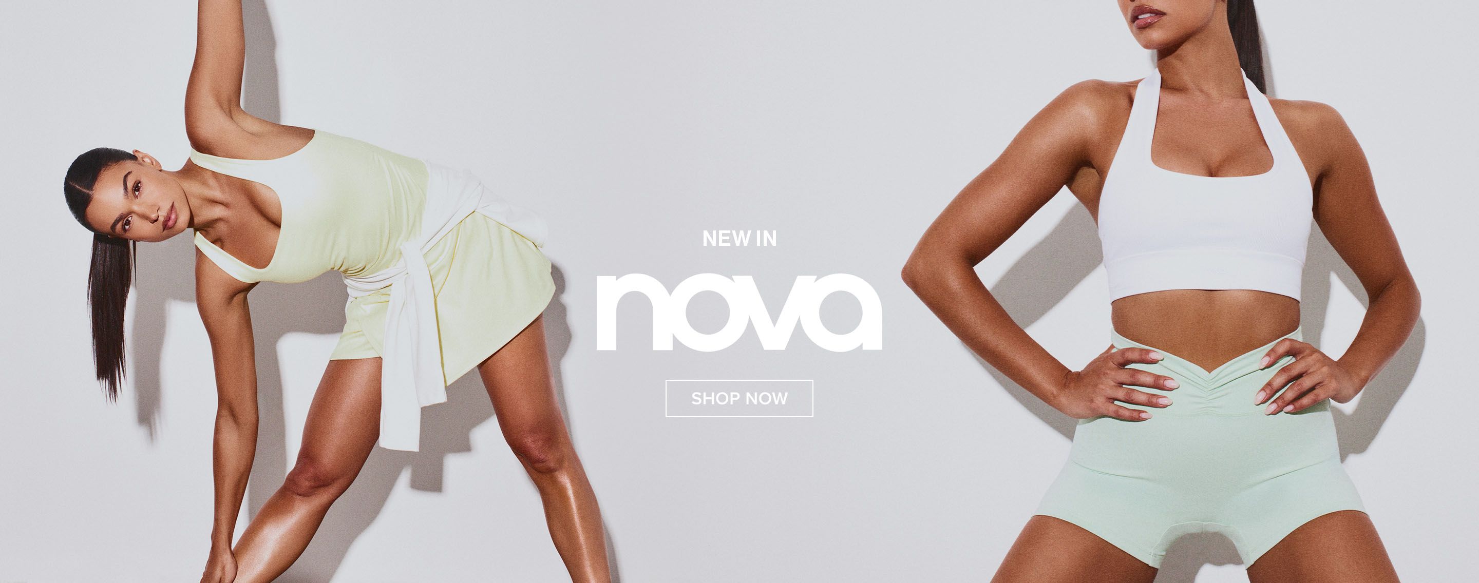 Woman models Nova new in activewear: white sports bra, light green ruched shorts. Hands on hips. Shop latest sportswear now.