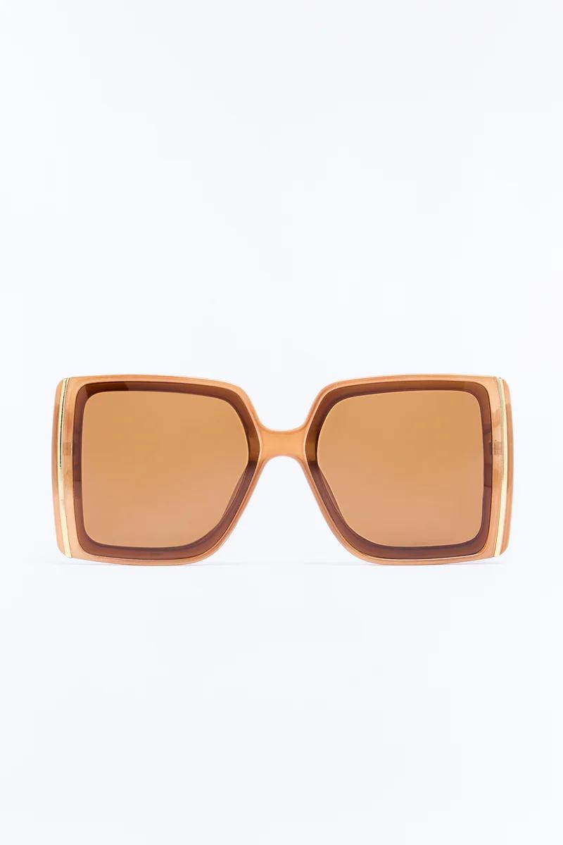 Gafas de sol cuadradas oversized con montura color melocotón y lentes ámbar, presentadas de frente para una colección de moda online.