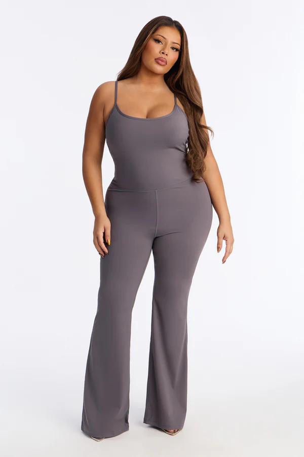 Mujer segura modelando mono de talla grande gris carbón con tirantes y pernera acampanada, destacando moda femenina cómoda.