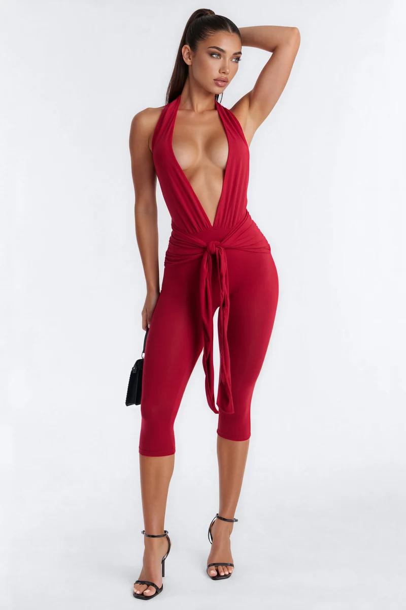 Elegant model in a chic red halter crop jumpsuit featuring a plunging neckline and waist tie, showcasing trendy party evening wear.