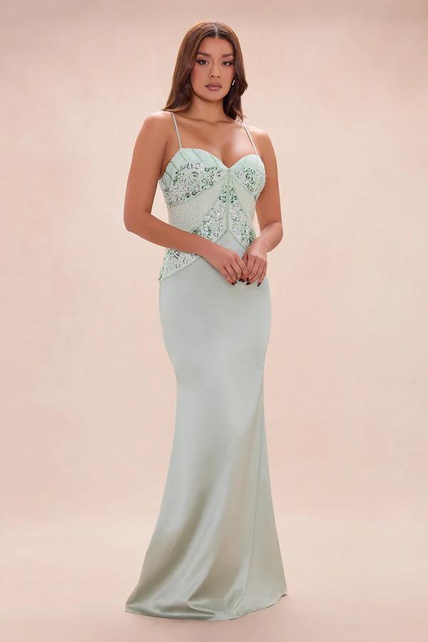 Elegant woman in a mint green formal gown with an embroidered bodice and spaghetti straps, perfect for evening wear or special occasions.