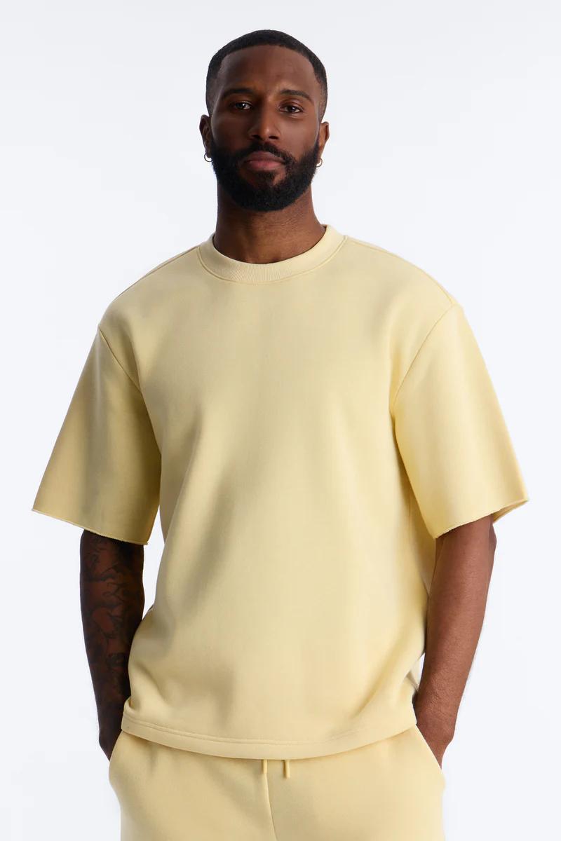 Hombre elegante con sudadera de manga corta y conjunto loungewear amarillo pálido a juego, promocionando moda casual cómoda.
