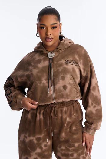 Woman in a brown and light brown tie-dye cropped hoodie with a "Von Dutch" logo and matching sweatpants, posing confidently.