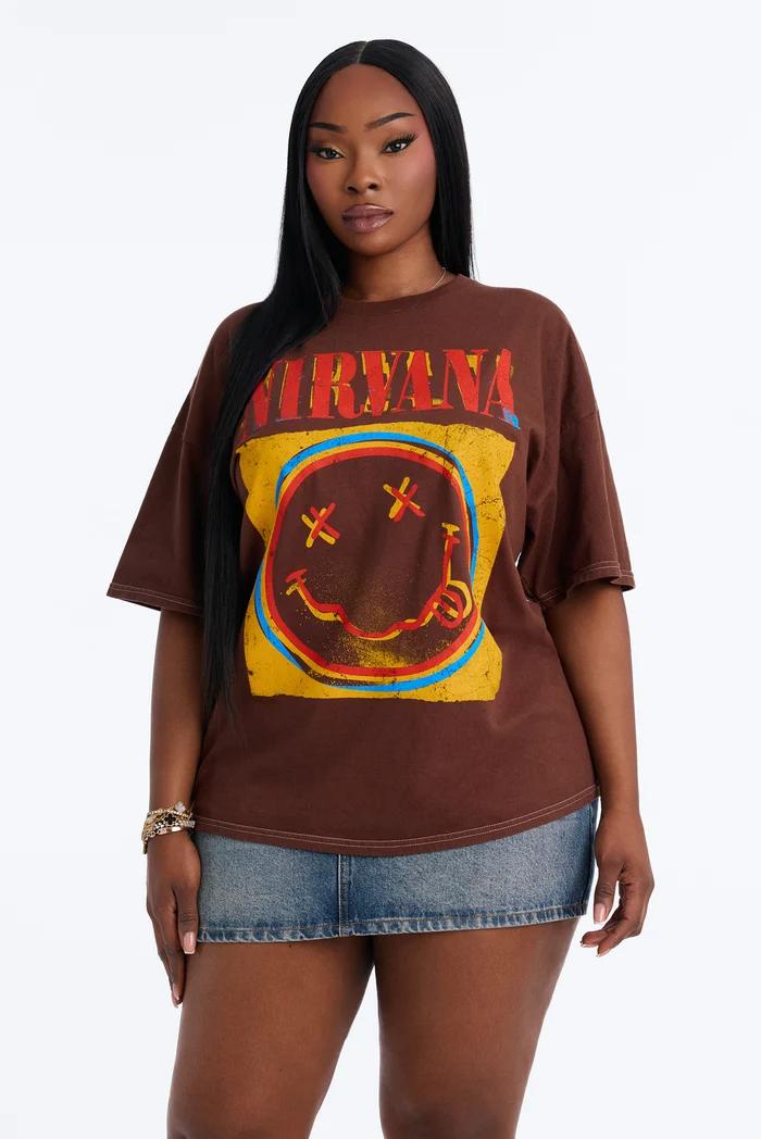 Plus-size woman wearing an oversized brown Nirvana graphic tee and denim miniskirt.