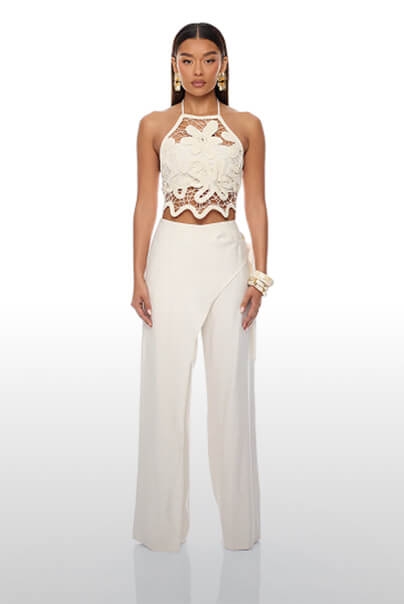 Elegante top halter de crochet color crema con flores y pantalones anchos con solapa en modelo, ideal para moda resort chic.