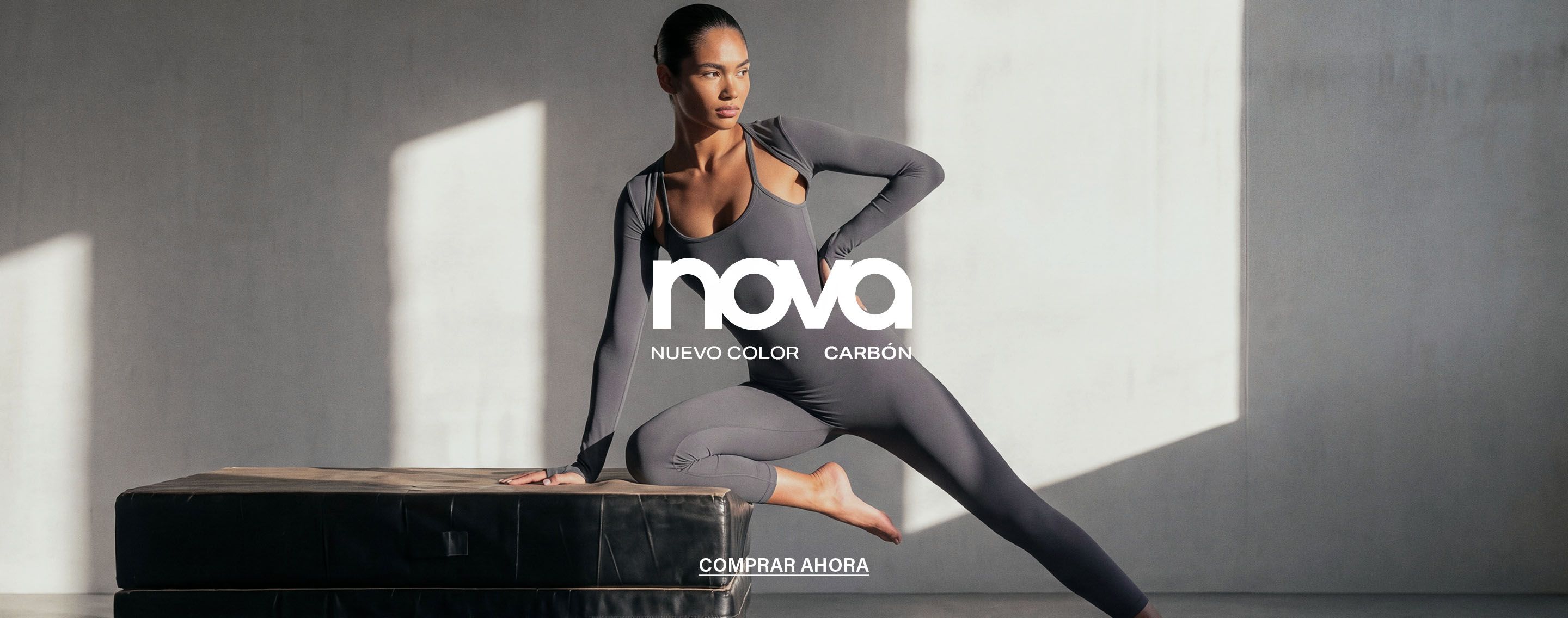 Modelo realiza una pose dinámica en un mono de gimnasia gris de Nova, promocionando la nueva colección de ropa deportiva color carbón.