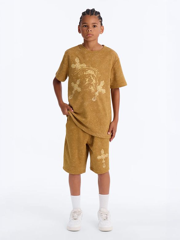 Boy in mustard acid-wash t-shirt and shorts set featuring gold Jesus graphic and crosses, promoting versatile youth casual wear.