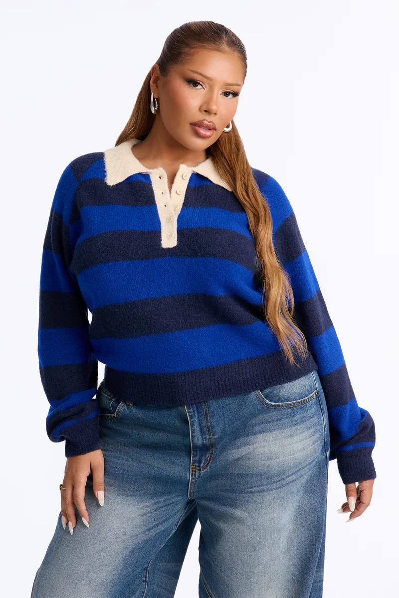 Plus size woman in a blue striped polo sweater with a cream collar and jeans.