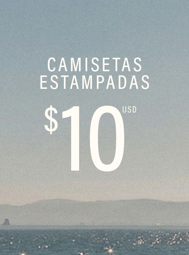 Texto blanco "CAMISETAS ESTAMPADAS $10 USD" sobre fondo de cielo azul, montañas y mar brillante. Promoción de camisetas estampadas.
