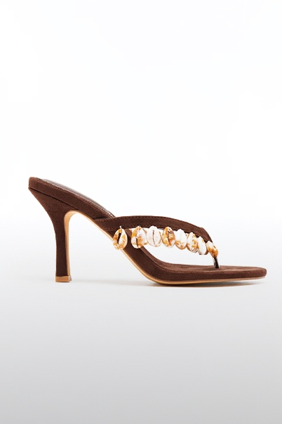 Elegante sandalia de tacón marrón oscuro, con tira entre los dedos y adornos de conchas naturales, ideal para elevar atuendos de verano.