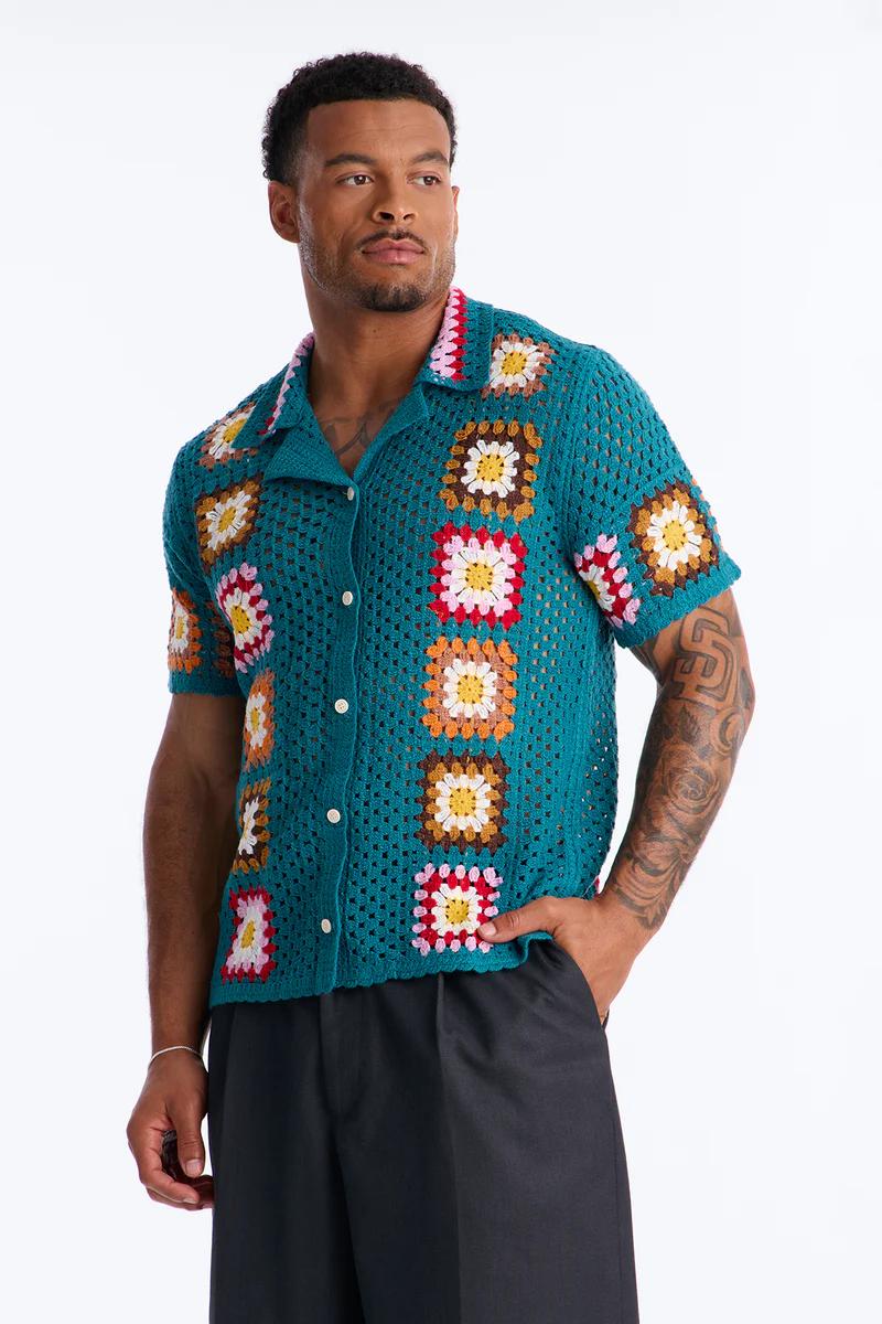 Hombre con camisa de ganchillo turquesa de manga corta, con coloridos diseños cuadrados. Ideal para moda de verano.
