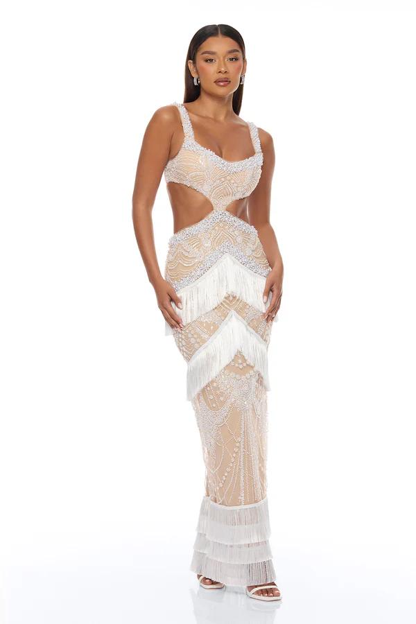 Elegant model wearing a shimmering periwinkle, form-fitting, full-length gown with spaghetti straps and a sculpted bustier top. White background.