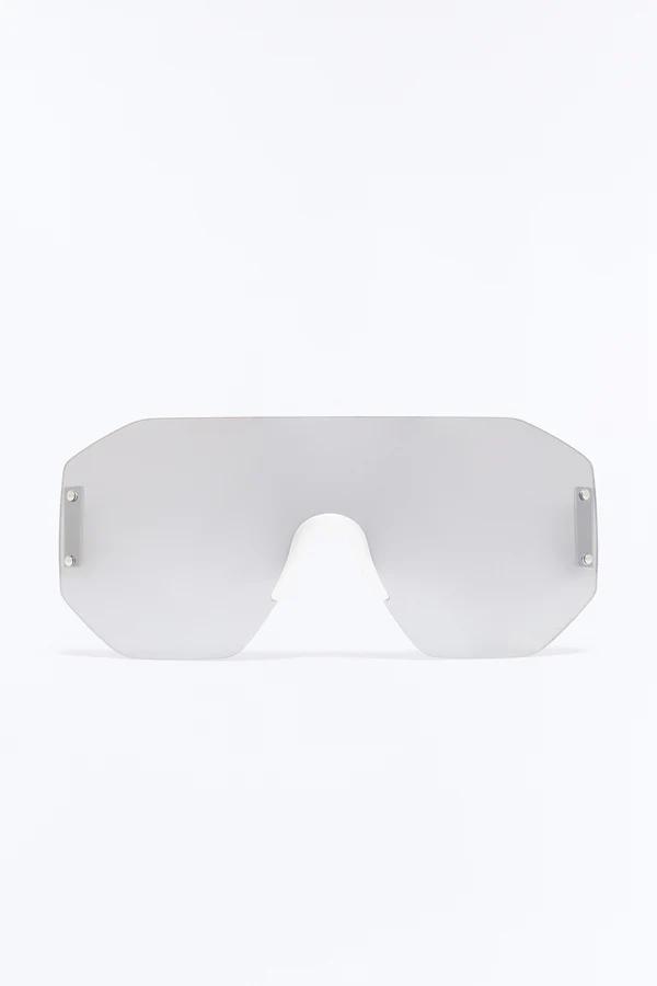 Modern, oversized, frameless shield sunglasses with light silver-grey mirrored lenses and subtle side attachments, centered on a clean white background.