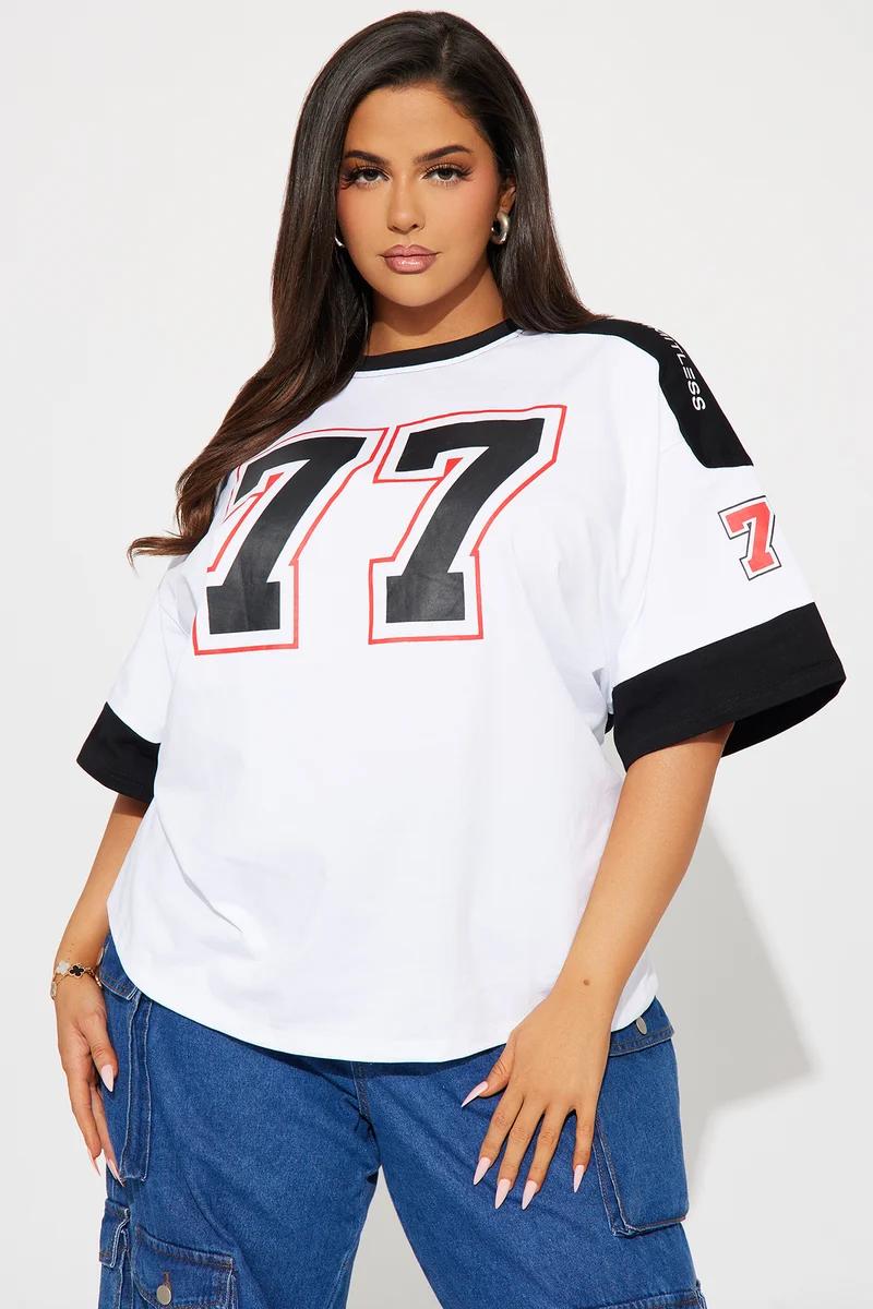 Plus size woman wearing a white oversized jersey t-shirt with number 77 and blue jeans.