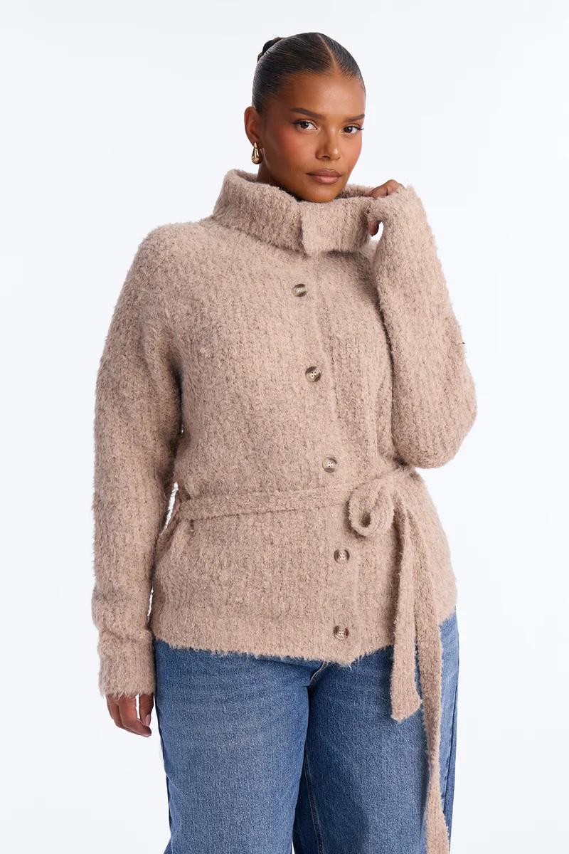 Plus size woman in a cozy beige fuzzy knit cardigan jacket with high neck, button front, and waist belt.