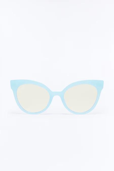 Elegantes gafas de sol cat-eye azul claro con montura ancha y lentes amarillas pálidas sutiles, destacadas sobre fondo blanco liso.