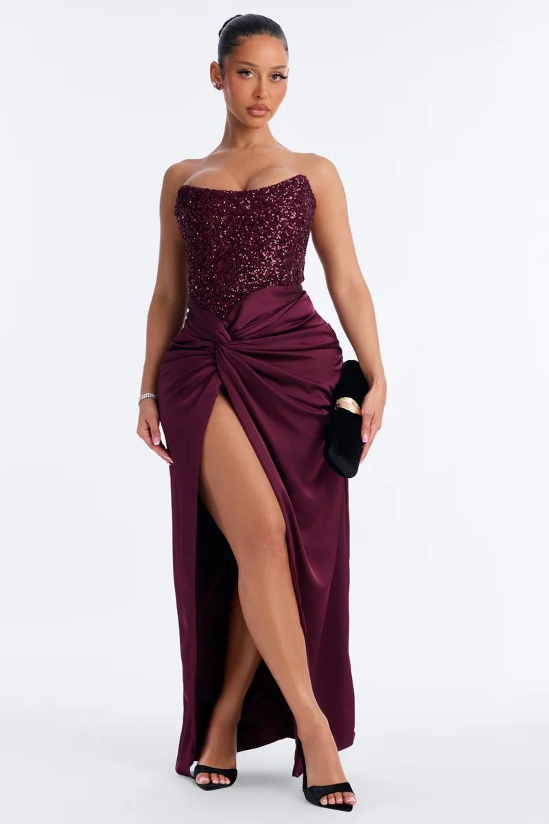 Model wears a burgundy sequin corset evening gown with a high-slit satin skirt, showcasing a glamour formal dress collection for galas.