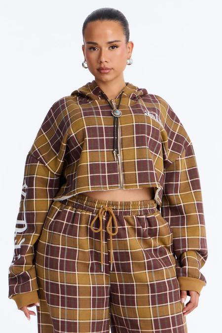 Mujer luciendo una cómoda sudadera corta con capucha y joggers a juego de cuadros marrones y granates, destacando nuestro nuevo conjunto loungewear.